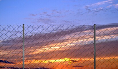 Mesh wire fence and sunset sky - 3d illustration