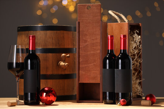 Bottles of wine, glass, wooden gift boxes, barrel corks and red Christmas balls on table