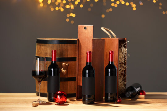 Bottles of wine, glass, wooden gift boxes, barrel corks and red Christmas balls on table