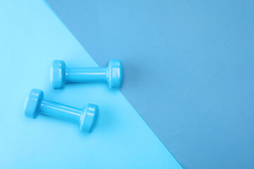 Two dumbbells on blue background, top view. Space for text