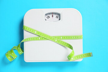 Scale tied with measuring tape on light blue background, top view