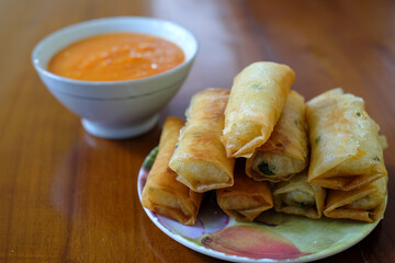 Fried spring rolls on white plate, served with chili sauce sambal on top the wood table, traditional snack, Traditional spring rolls, copy space .