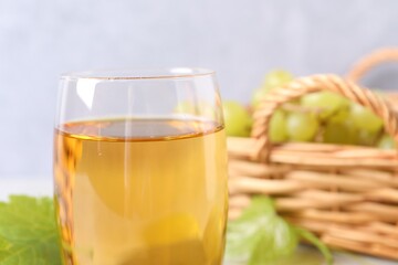 Tasty grape juice in glass on blurred background, closeup