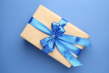 Gift box with bow on blue background, top view