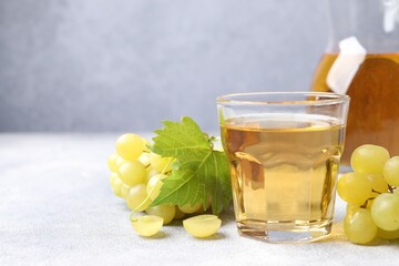 Ripe grapes and tasty juice on grey table. Space for text