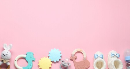Colorful rattles and pacifier on pale pink background, flat lay with space for text. Baby...