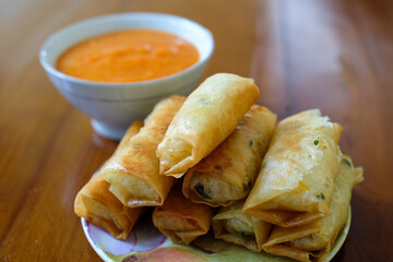 Fried spring rolls on white plate, served with chili sauce sambal on top the wood table, traditional snack, Traditional spring rolls, copy space .