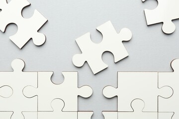 Obraz premium White puzzle pieces on grey background, top view