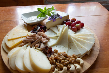 Table of different cheeses presented with grapes, nuts, some mint leaves and lavender flowers