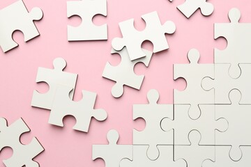 White puzzle pieces on pink background, top view