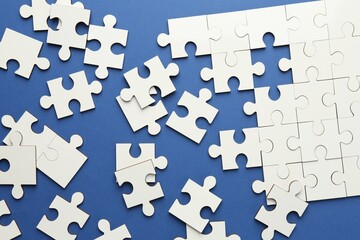 Obraz premium White puzzle pieces on blue background, top view