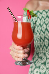 Woman with glass of refreshing cocktail on pink background, closeup