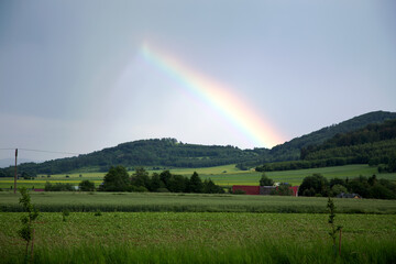 Tęcza nad górami, zielone pola, dachy domów. © Stanisław Błachowicz