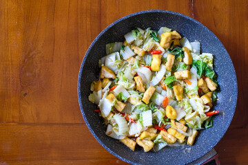 Stir fry tofu and chinese cabbage in  the pan on a wood table, Indonesian dish eaten with rice.