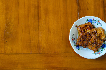 Tempeh and Tahu Bacem in white plate on the wood table, traditional Indonesian dishes with a sweet taste.