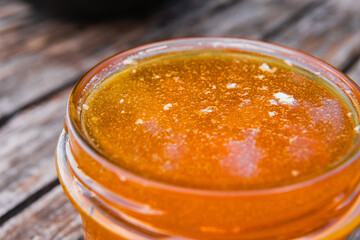 Honey Jar Filled to the Brim with Fresh Honey Standing on a Wooden SurfaceExtreme Close Up