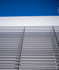 Abstract Geometric Background of a White Wall with Silver Stanchions and Blue Sky Overhead.