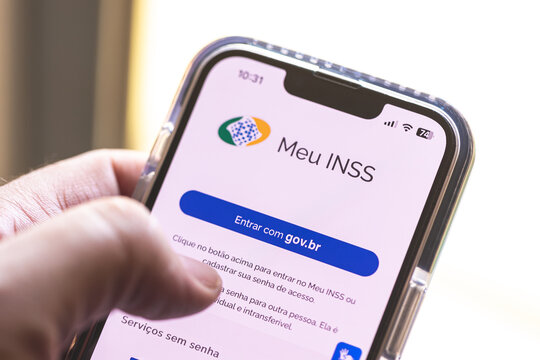 O aplicativo: Meu INSS, na tela de um smartphone que um homem est&aacute; segurando. Instituto Nacional do Seguro Social. Foto em closeup. Brasil, 19 de Julho de 2024.