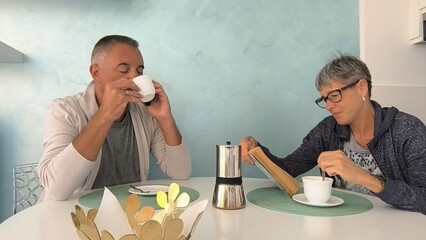 Young couple sitting at the table in their home, having breakfast. Breakfast at home with friends. Couple in harmony who have breakfast at home every day