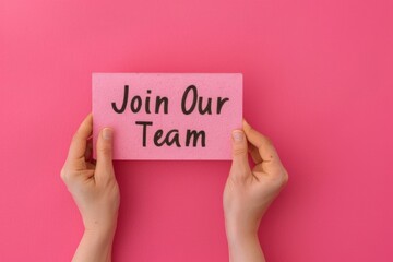 Hands Holding a 'Join Our Team' Sign Against a Pink Background