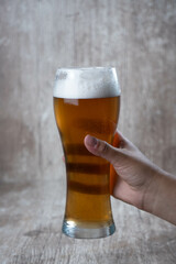 female hand raising beer on wooden background