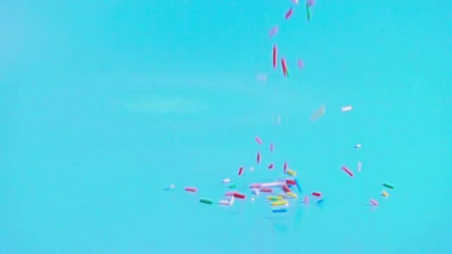 colorful sprinkles falling on blue background, decoration for cake and bakery, super slow motion