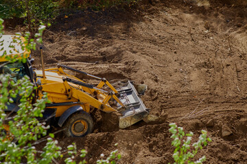 Earthworks at the construction site: bulldozer leveling the ground against greenery.