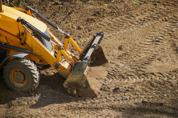 Front part of yellow bulldozer with bucket on construction site, bulldozer operation on a dirt site