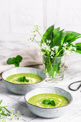 Two bowls of wild garlic soup on light gray background