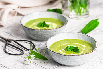 Two bowls of wild garlic soup on light gray background