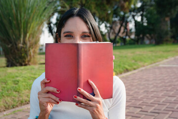 Portrait of shy Woman covering her face with book