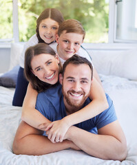 Obraz premium Happy family, portrait and bed with hug for bonding, holiday or weekend together at home. Mother, father and playful children on back with smile for morning, wake up or lying in bedroom at house