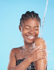 Black woman, happy and splash of water in studio for cleaning face, hygiene and skincare beauty of hydrate glow. Smile, female person and natural facial, cosmetics and wellness on blue background