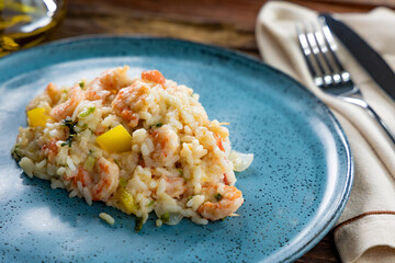 Risotto de camarão na mesa de madeira e prato azul (arroz de camarão)