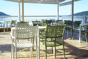 Small business on the coast of Montenegro: an open cafe with no people. Empty tables and free chairs standing on the terrace overlooking the sea.