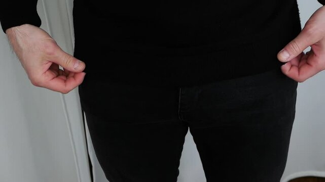 A man zips up his jeans. Fasten the lock on men's denim pants.