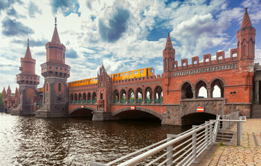 Obraz premium Yellow carriages of the famous Berlin metro on the Oberbaum Bridge on a sunny day.