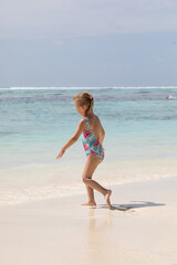 Fototapeta premium Young girl running joyfully on the beach, white sand, vitamin d, holidays with children, summer holidays