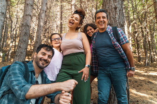 Happy diverse family enjoying outdoor hike in forest, multigenerational group laughing together, inclusive vacation concept