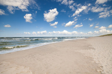Empty, sandy beach and sea waves by sunny day