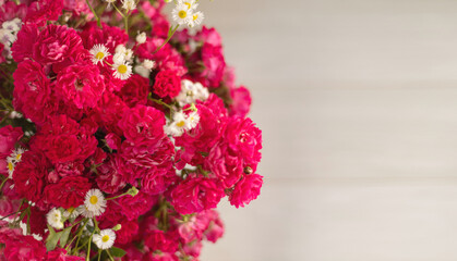 A large bouquet of small, bushy red roses on the left. Close up. Place for text