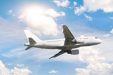 Flying airplane. Travel background with white commercial airplane flying in the blue sky