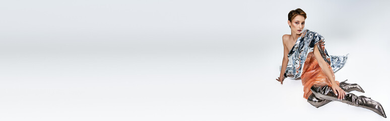 A woman in a sustainable fashion outfit sits gracefully on a white backdrop.