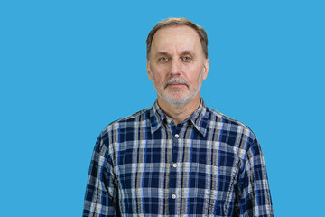 Obraz premium Portrait of confident aged senior man in checkered shirt. Isolated in blue background.