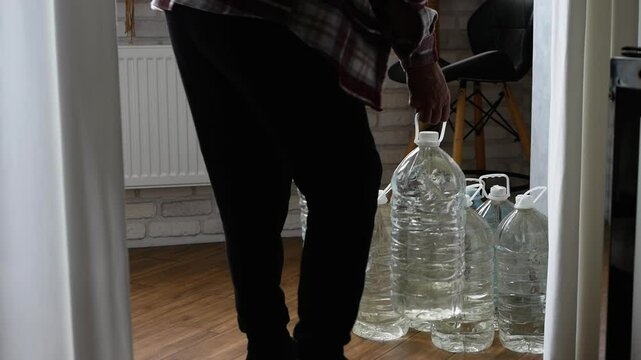 A man with a bottle of drinking water in his hands. Drinking water supply. Concept Drought climate change. Emergency service water at home.