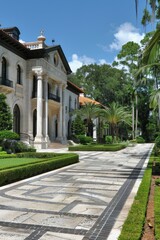 Elegant spanish style home with white and black exterior, dark brown accents, and paver driveway