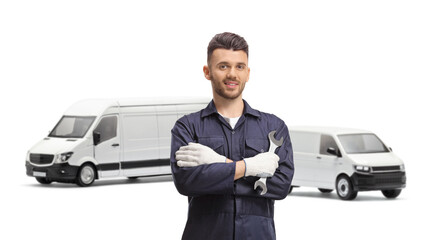 Auto mechanic holding a wrench and posing in front of vans