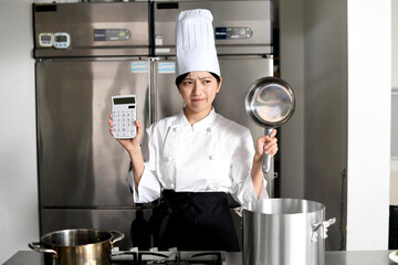 鍋と電卓を持ち悩むアジア人の女性調理師