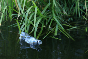 Plastic bottle in water, lake or river. Plastic pollution. Pollution of reservoirs and rivers. Garbage in the river close-up. An abandoned bottle floats on the lake. Food plastic in river water