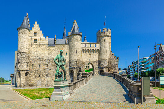 Antwerp, Belgium, July 7, 2023: Het Steen medieval fortress, stone castle with towers and Lange Wapper Statue on bank of Scheldt river in Antwerp city centre, Antwerpen old town, Flemish Region